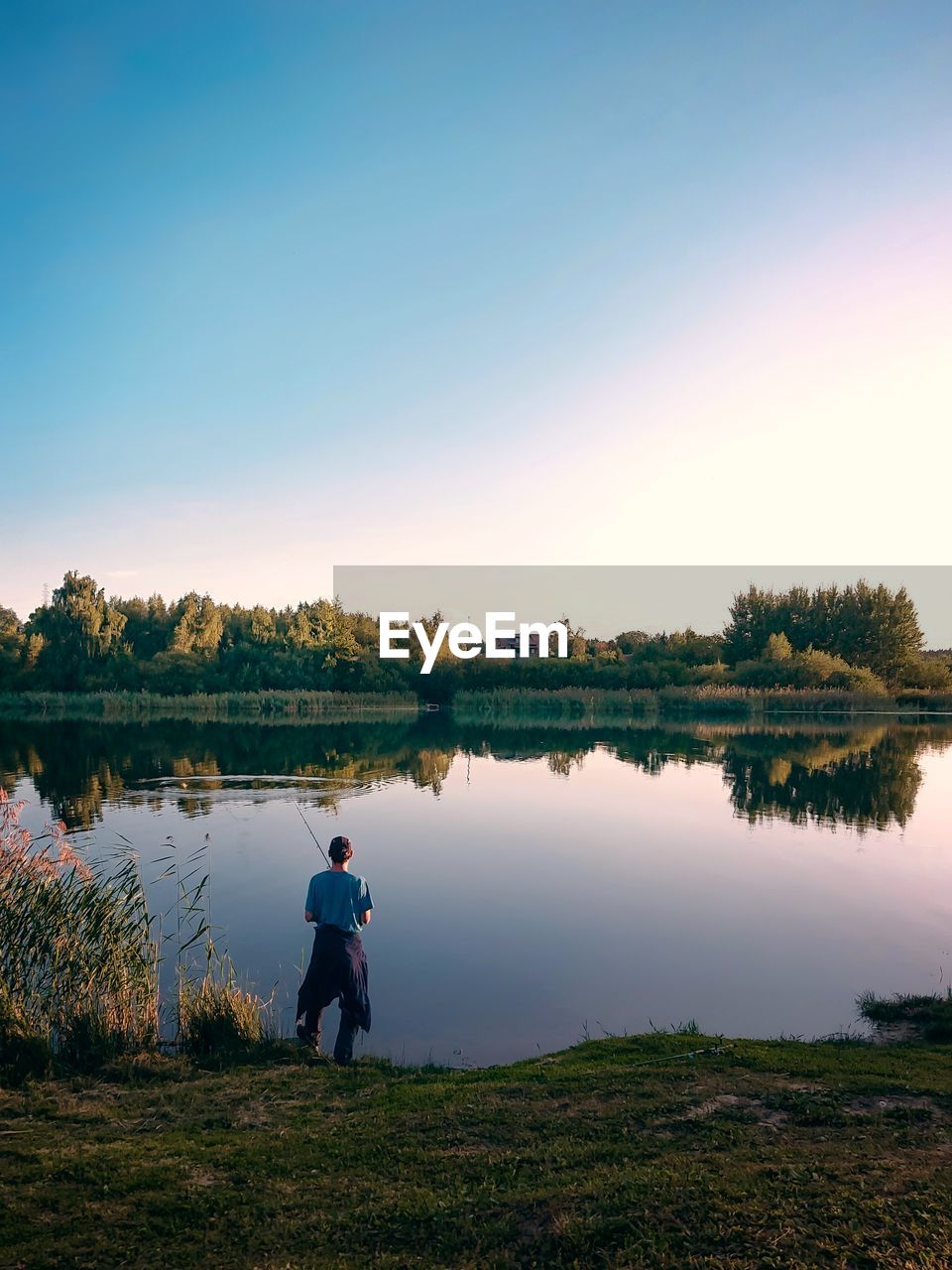 Man standing by lake against sky