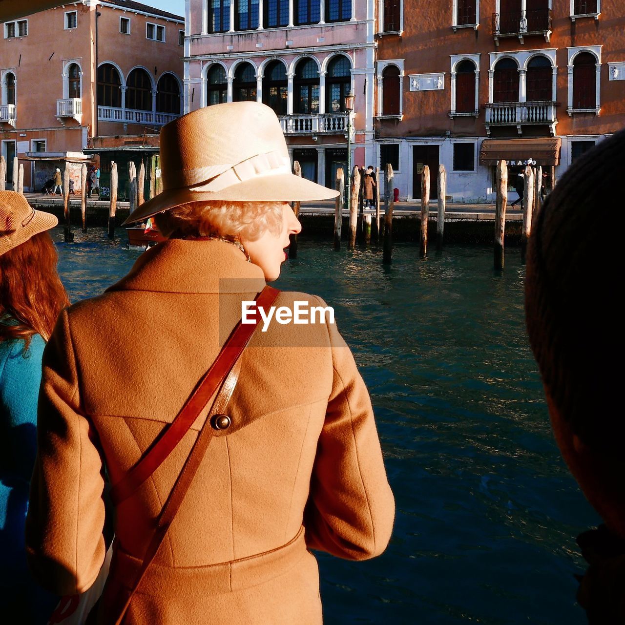 Rear view of woman standing by canal in city