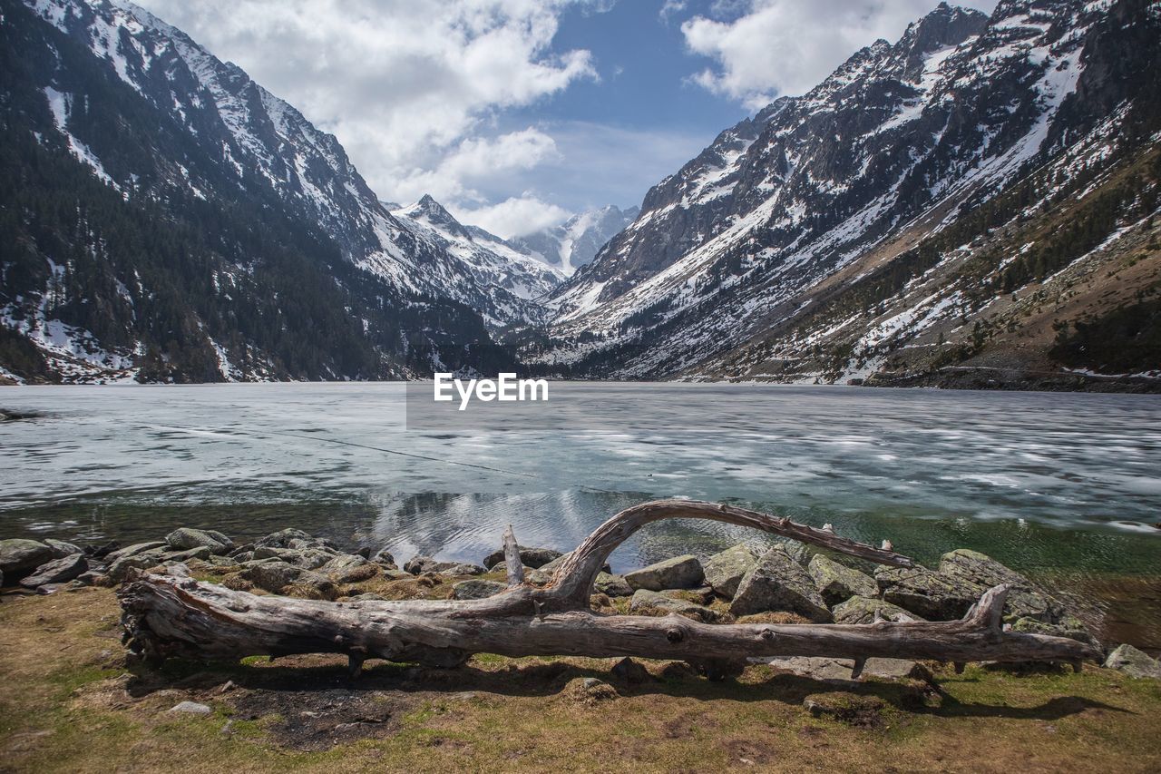 Scenic view of lake by snowcapped mountains against sky