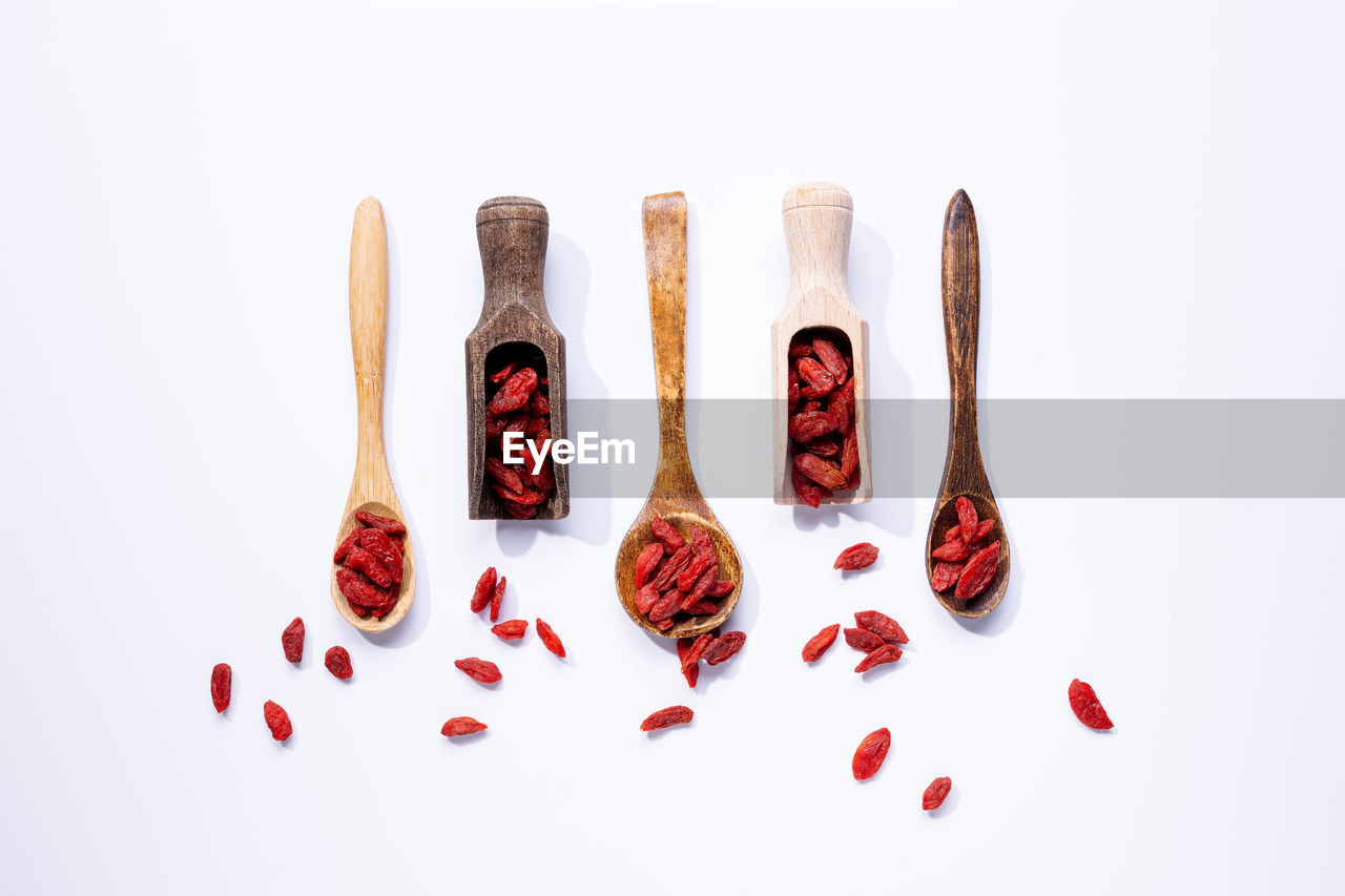 Dried goji berries on wooden spoons isolated on white background.