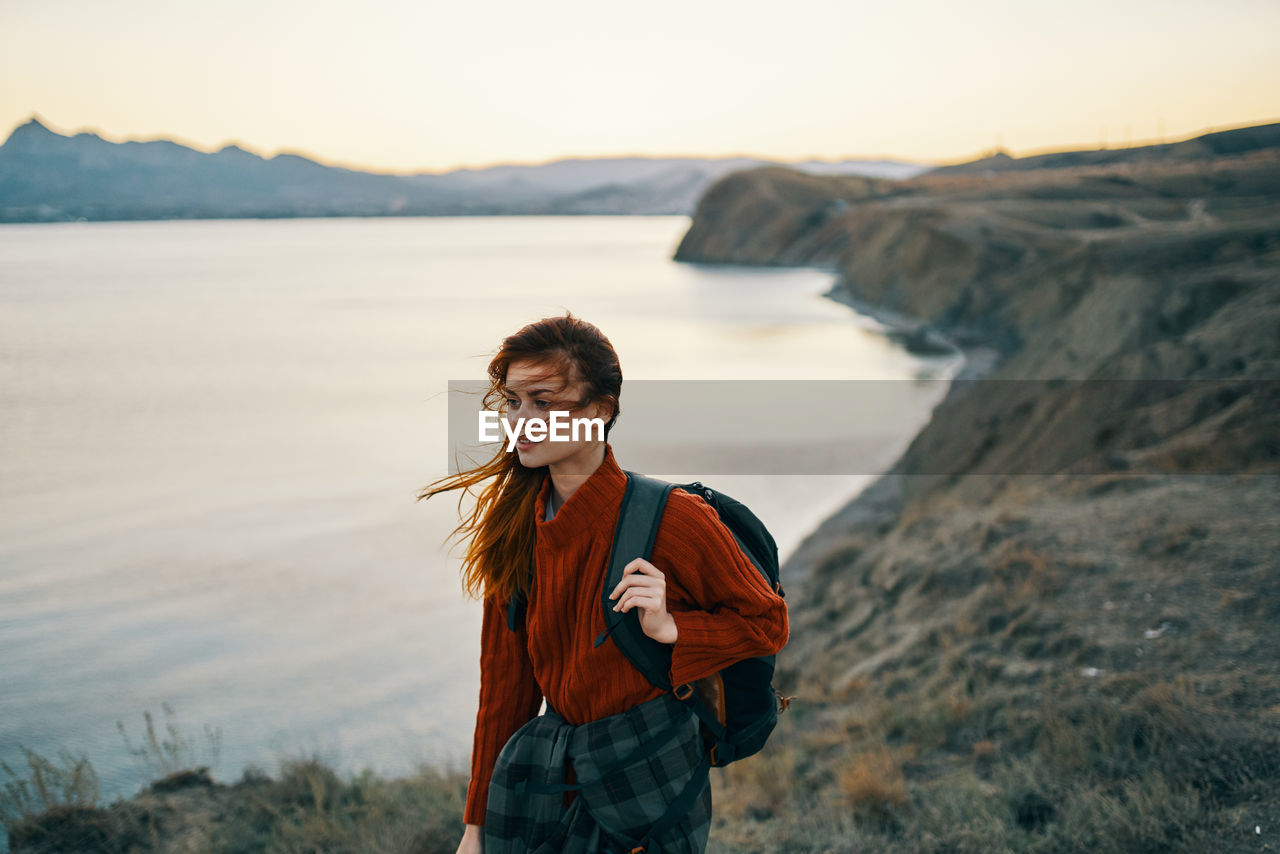 YOUNG WOMAN STANDING IN WATER AT SUNSET