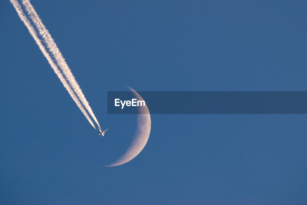 Low angle view of airplane flying against clear blue sky