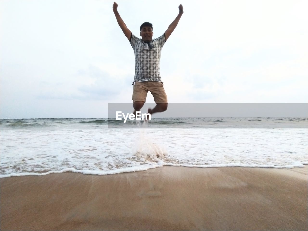 Full length of man jumping at beach against sky