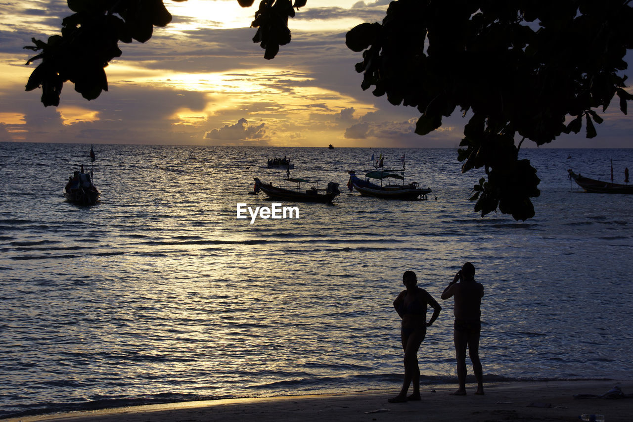 SILHOUETTE OF PEOPLE ON BEACH AT SUNSET