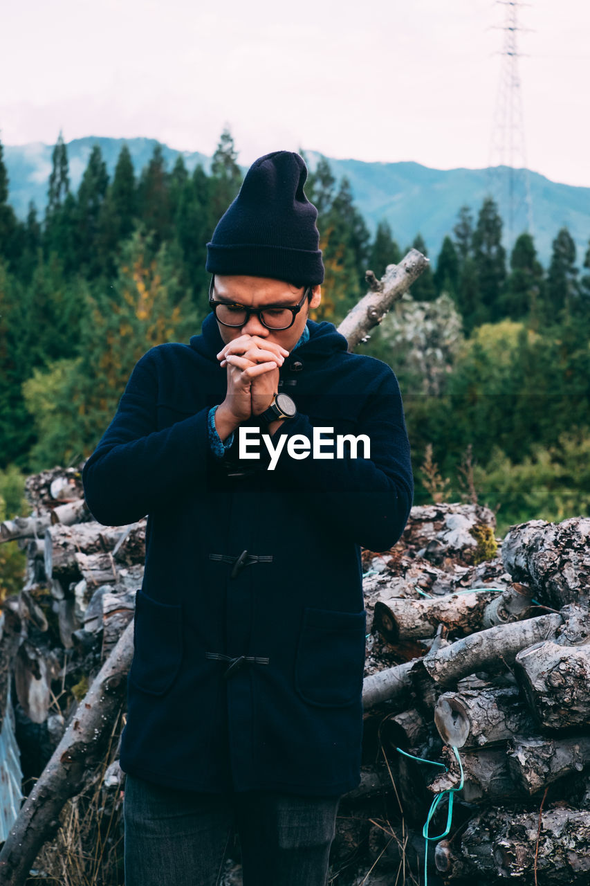 Man standing against logs in forest