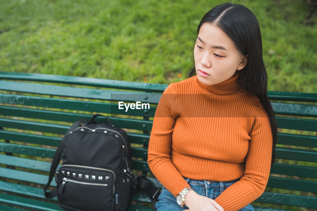 Thoughtful young woman sitting on bench