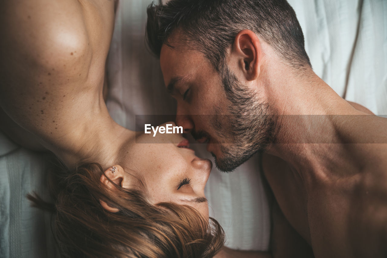 Directly above shot of shirtless couple on bed at home