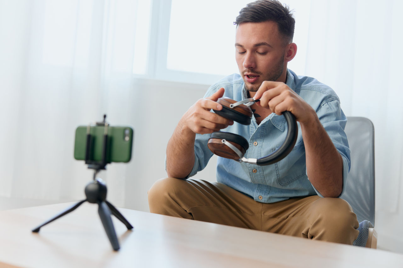 portrait of young man using mobile phone while sitting on table