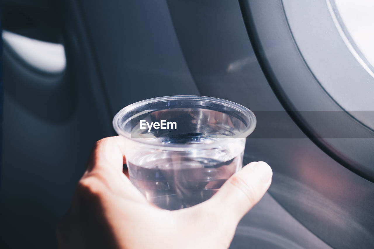 Cropped hand holding glass of water in car