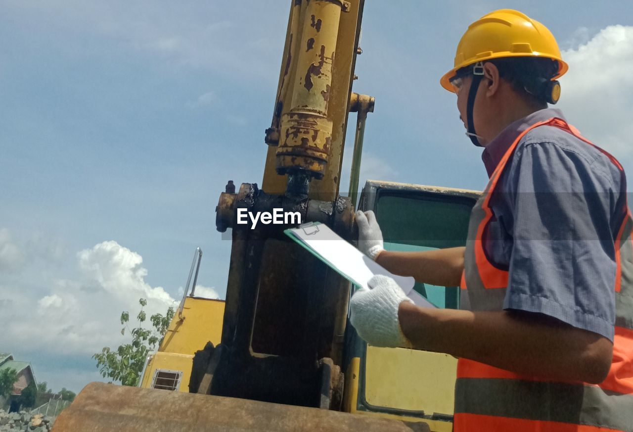 MAN WORKING ON CONSTRUCTION SITE AGAINST SKY