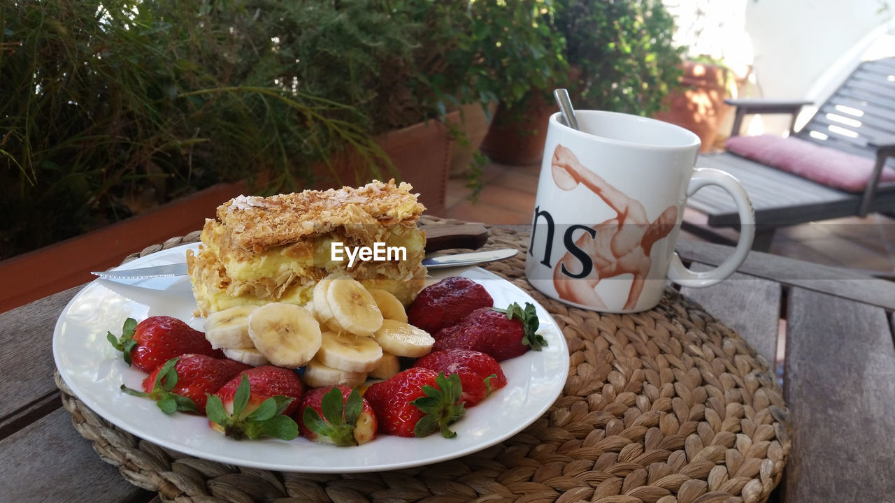 Close-up of fresh breakfast served with coffee on table in back yard