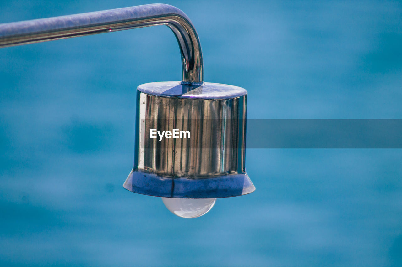 CLOSE-UP OF PADLOCK HANGING ON BLUE WATER