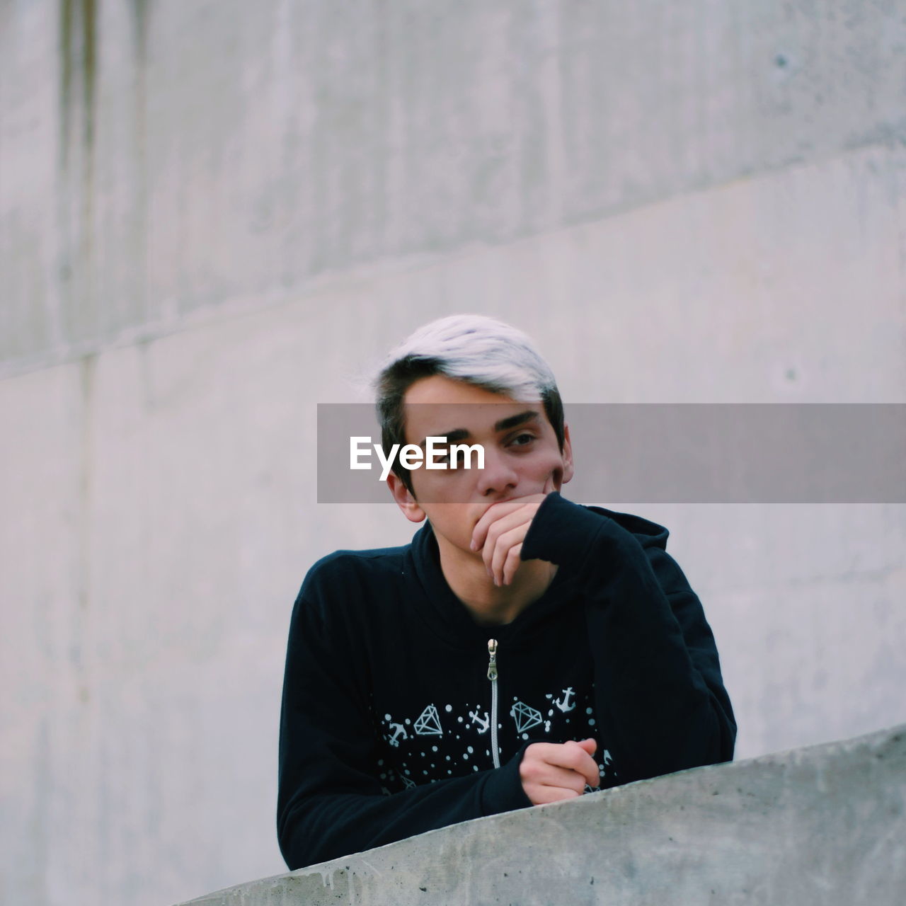 Thoughtful boy by retaining wall