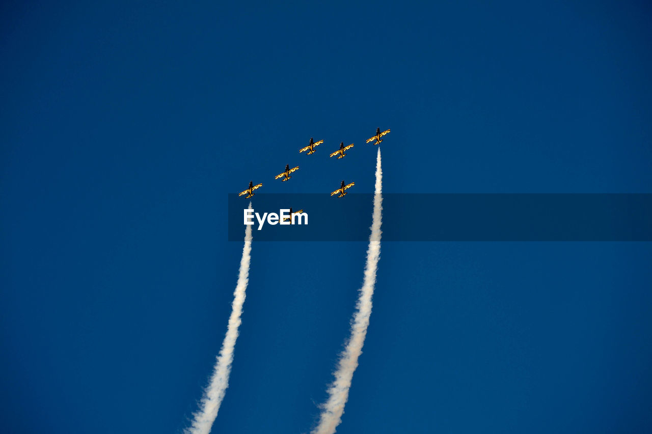 Low angle view of airplane flying against clear blue sky