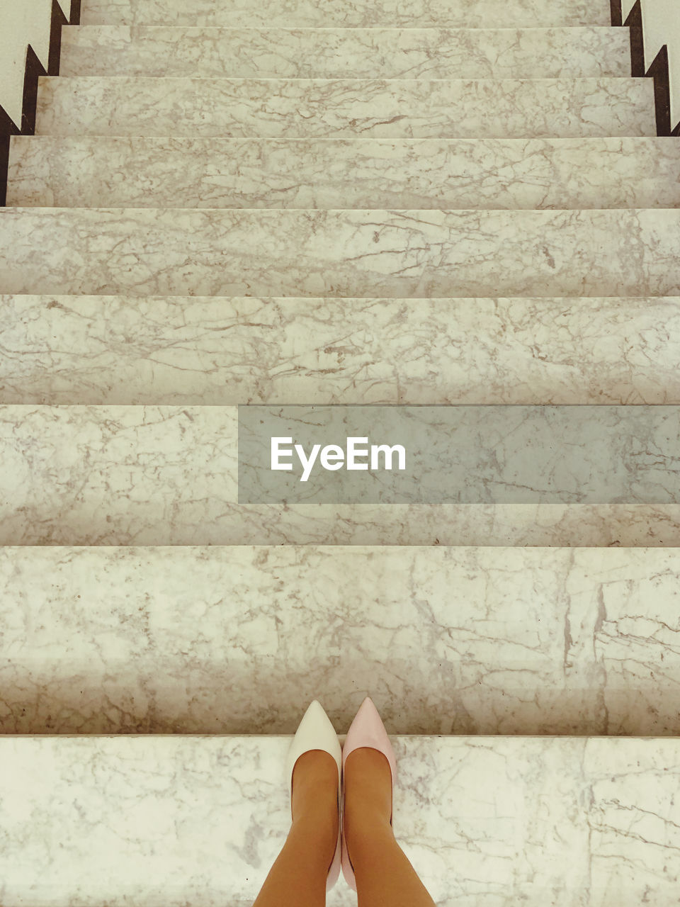 LOW SECTION VIEW OF WOMAN STANDING ON TILED FLOOR