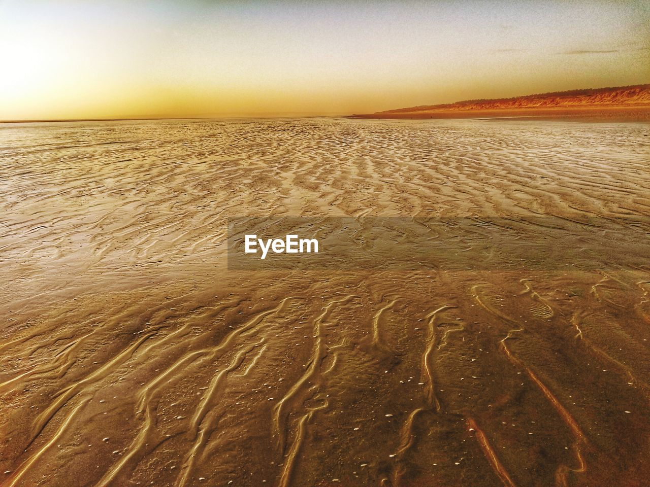 Scenic view of sandy beach at sunset