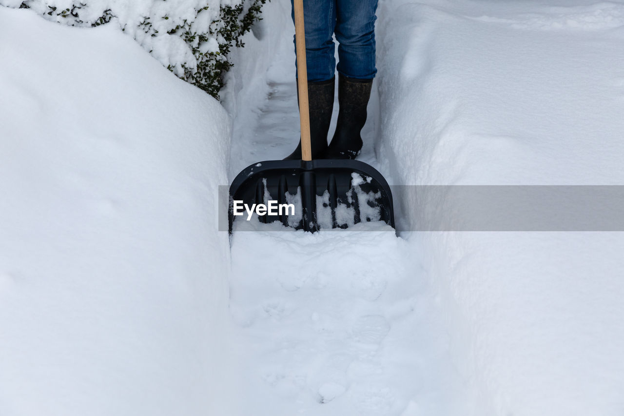 LOW SECTION OF PERSON WITH SNOW COVERED FIELD