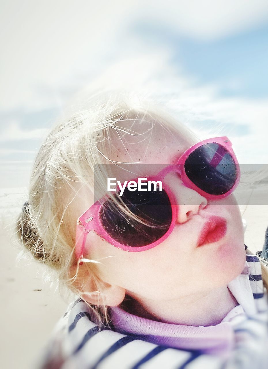 Close-up portrait of girl wearing sunglasses at beach against sky during sunny day