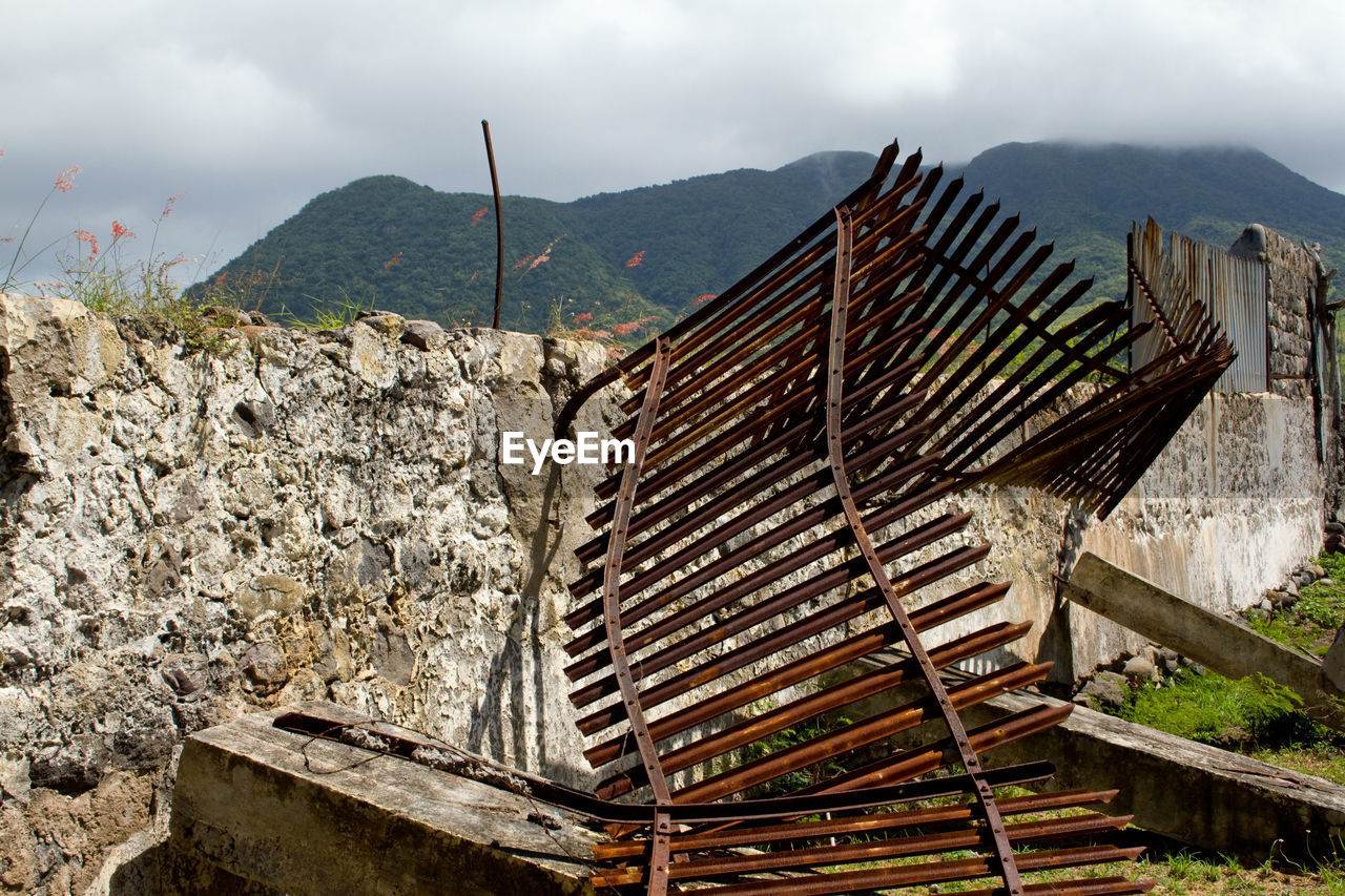 Panoramic view of rusty old fence and mountains against sky