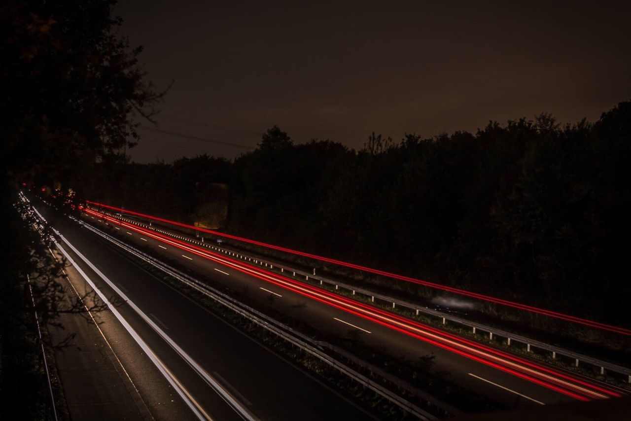 Light trails on road against sky at night