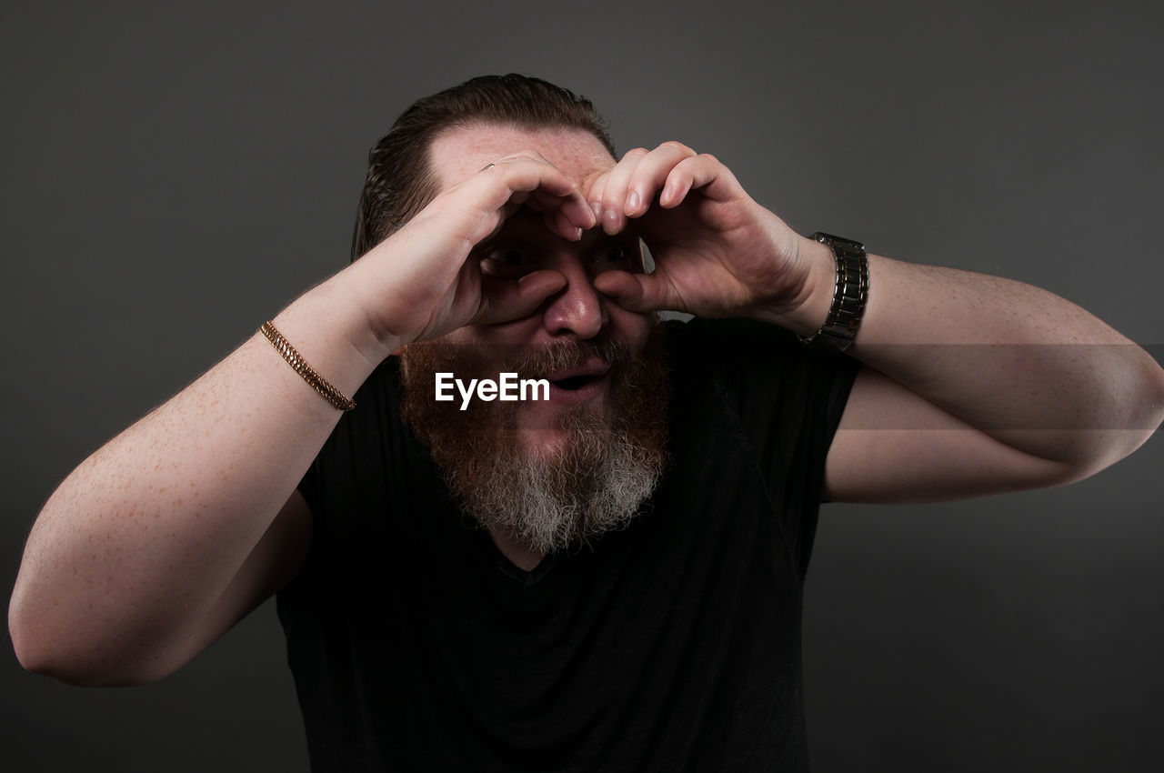 PORTRAIT OF MAN WEARING SUNGLASSES AGAINST BLACK BACKGROUND