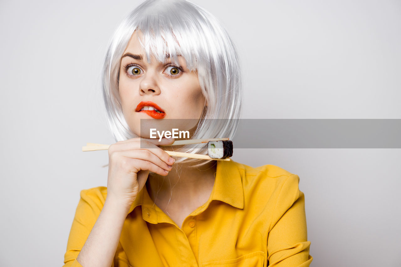 portrait, studio shot, women, one person, adult, blond hair, human face, wig, human hair, headshot, young adult, indoors, clothing, costume, looking at camera, person, female, yellow, human head, fashion, make-up, gray background, gray, bob cut, hairstyle, front view, lipstick, short hair, anime, human mouth, emotion, cartoon, nose, copy space, bangs, facial expression, glamour, bob, elegance