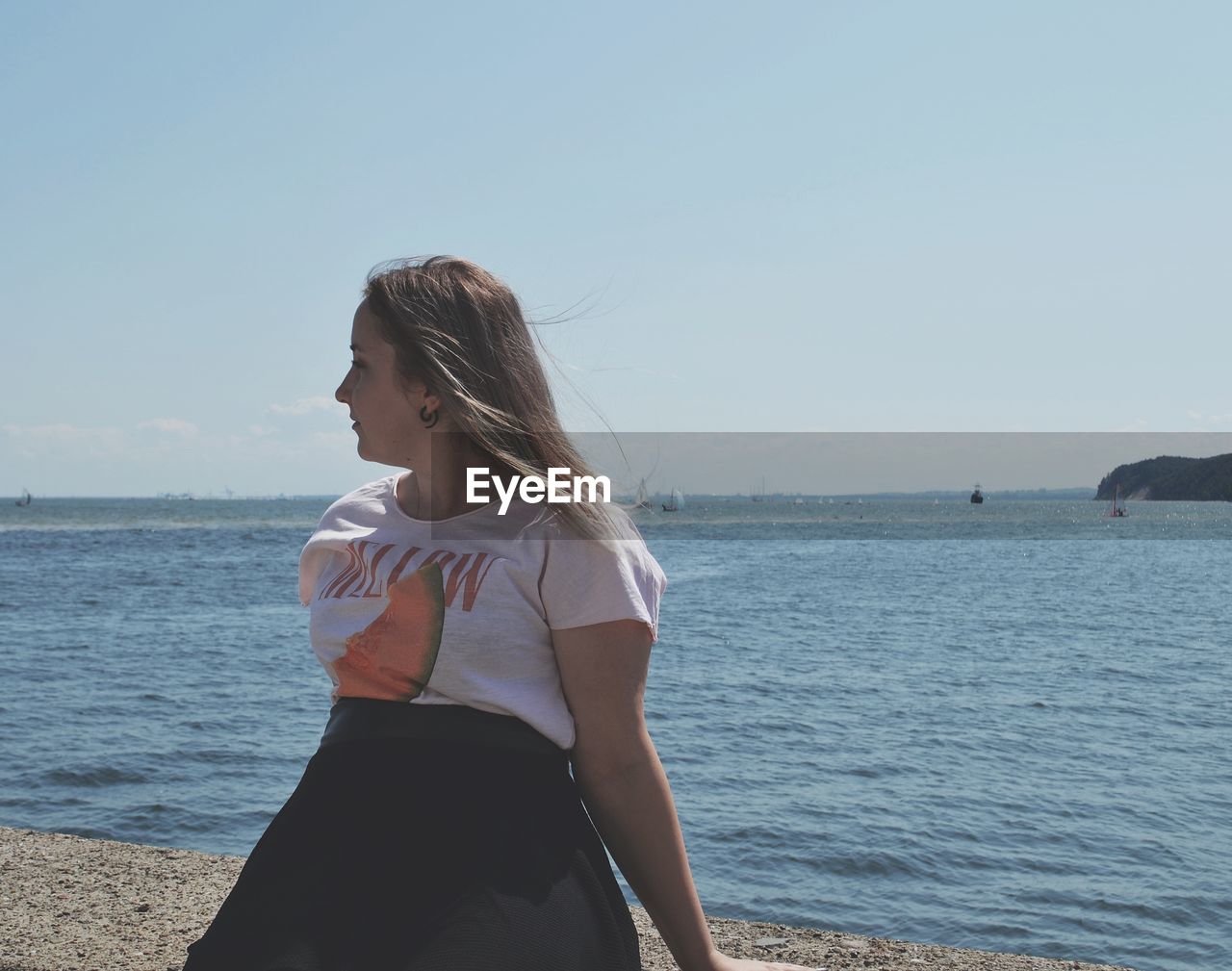 WOMAN STANDING BY SEA AGAINST SKY