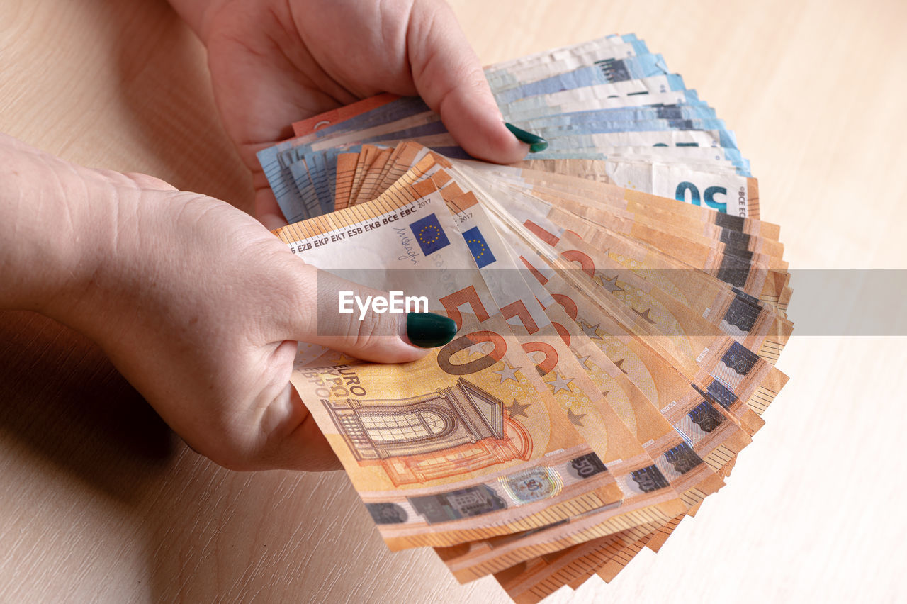 Business, finance, saving, banking and people concept - closeup of woman hands counting euro money