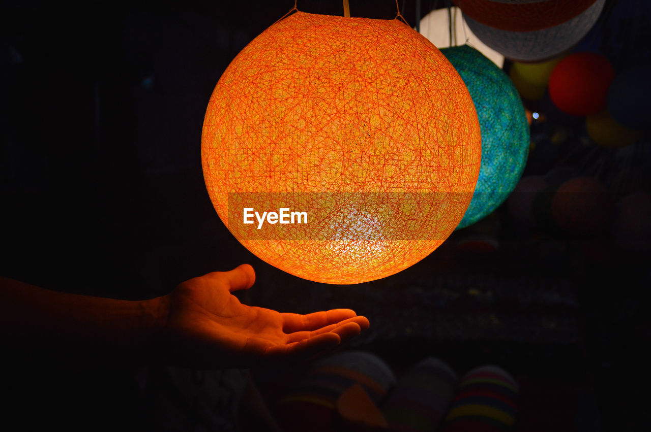 Close-up of hand holding orange laotian lantern