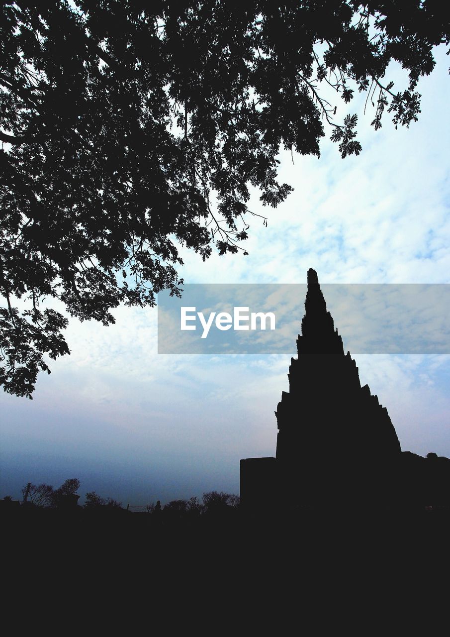 Silhouette of temple against cloudy sky