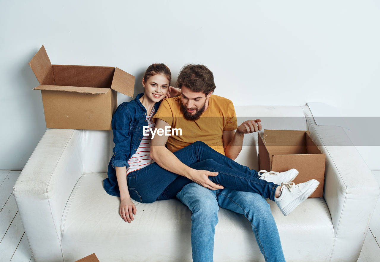 High angle view of couple sitting on sofa with cardboard boxes