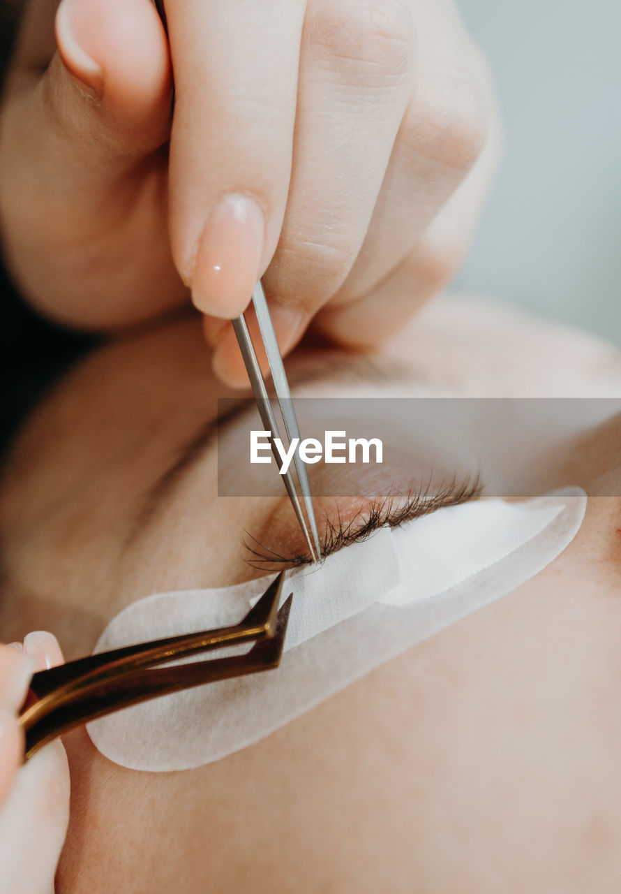 Portrait of a girl cosmetologist extending eyelashes to a woman.
