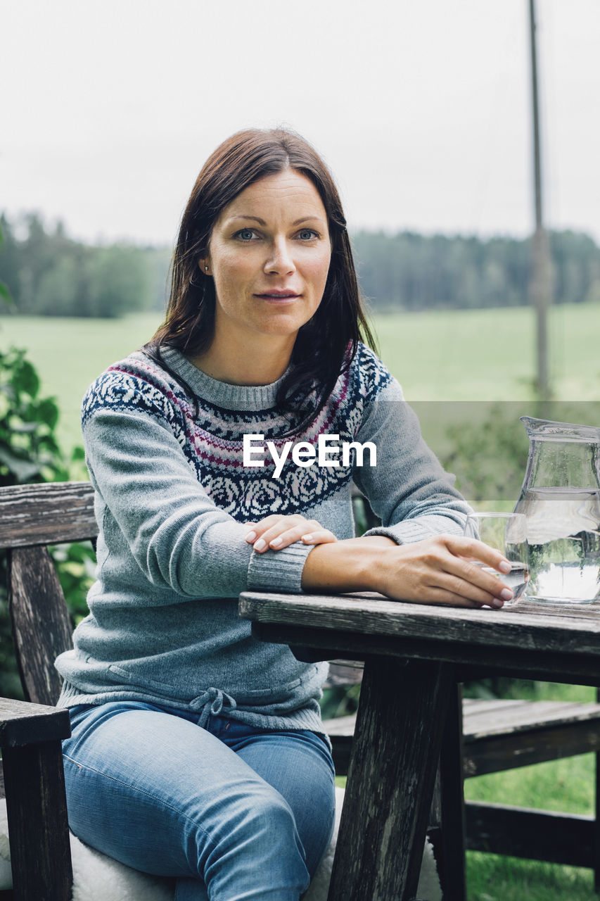 Portrait of confident woman sitting at table in organic farm
