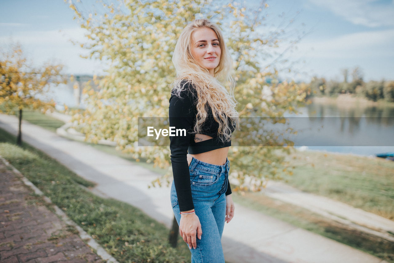 Portrait of beautiful young woman standing near water