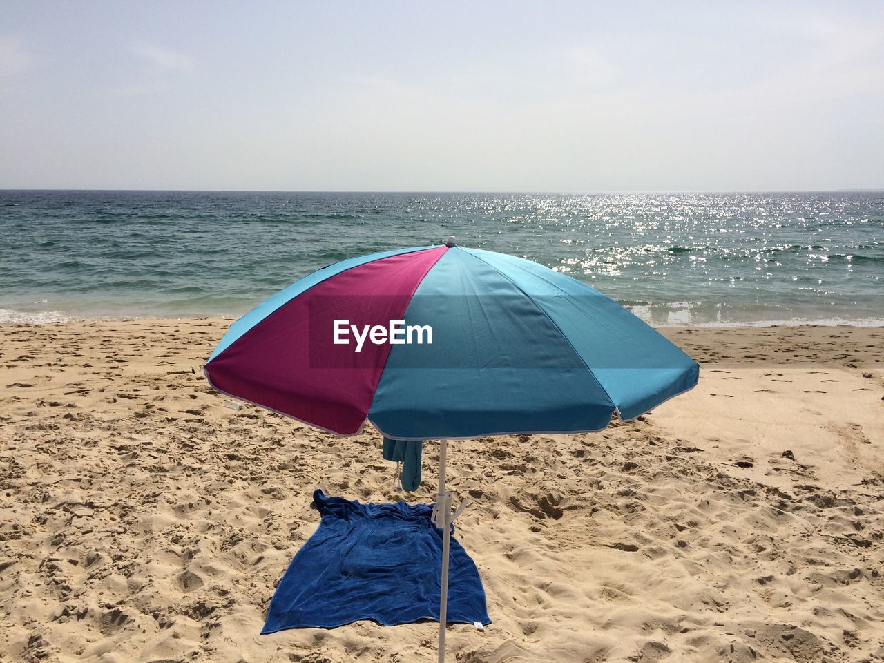 Sunshade and towel on beach during sunny day