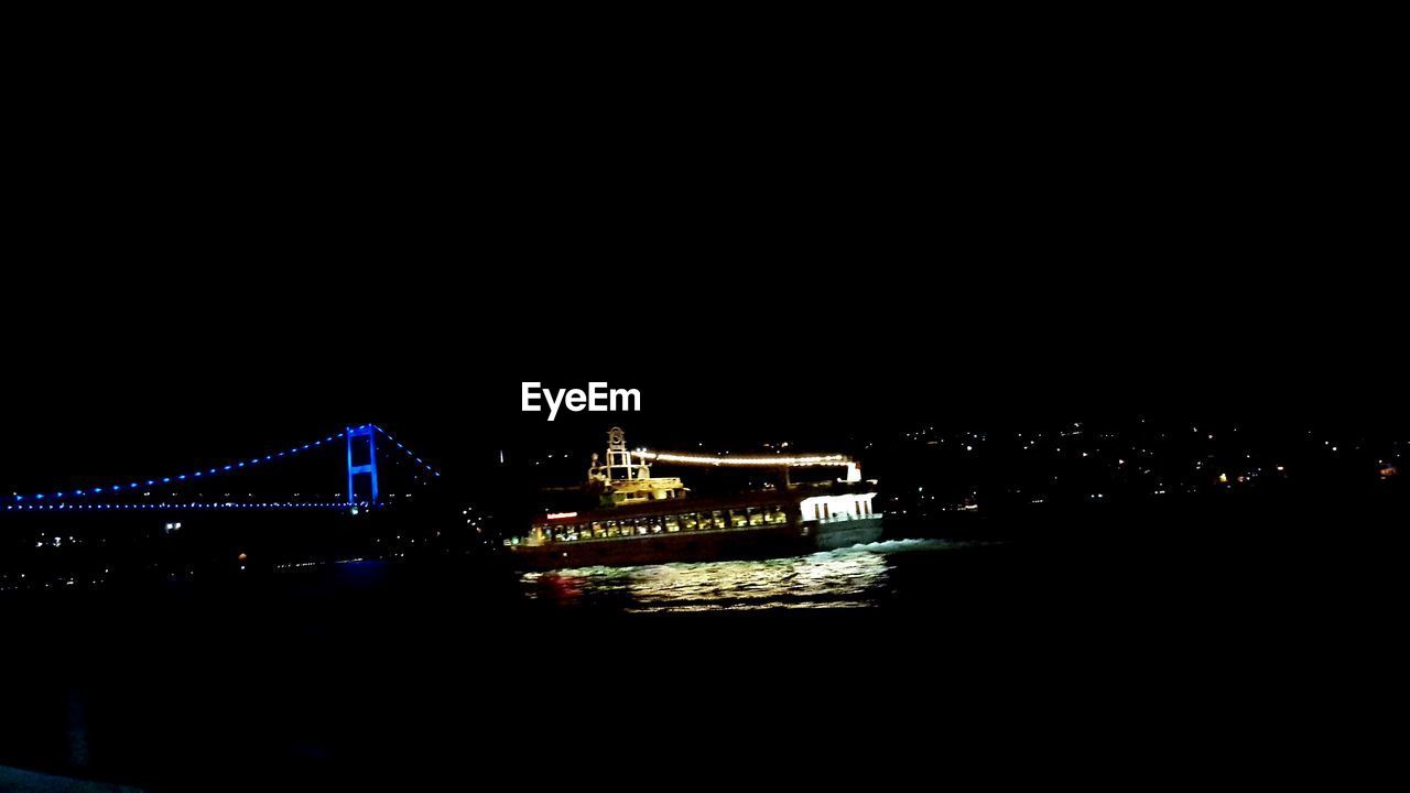 SUSPENSION BRIDGE OVER RIVER AT NIGHT