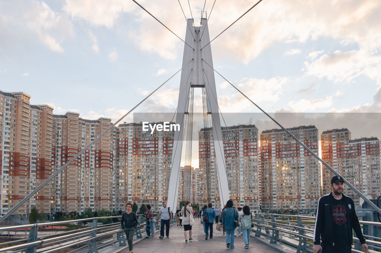 PEOPLE WALKING ON BRIDGE IN CITY