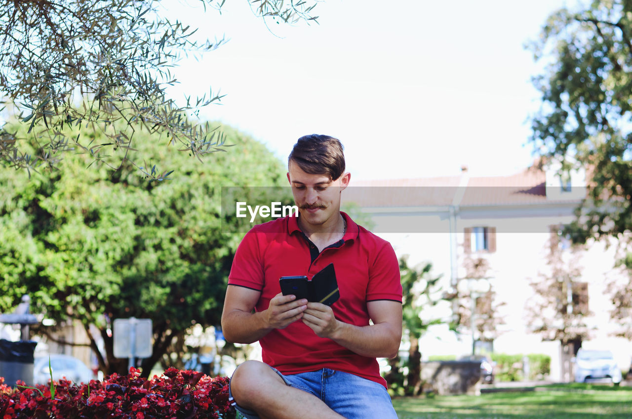 Young happy handsome bearded man, tourist sitting in green park. summer vacation. sunglasses.