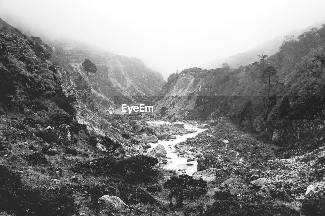 View of stream flowing between rocks against clear sky