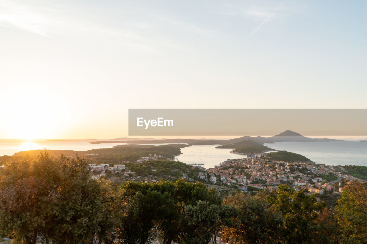 Aerial view of trees and sea against sky during sunset