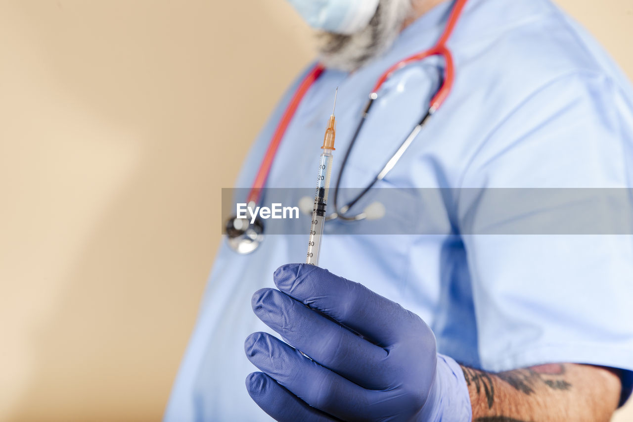 Close up of a male nurse holding a syringe with injection