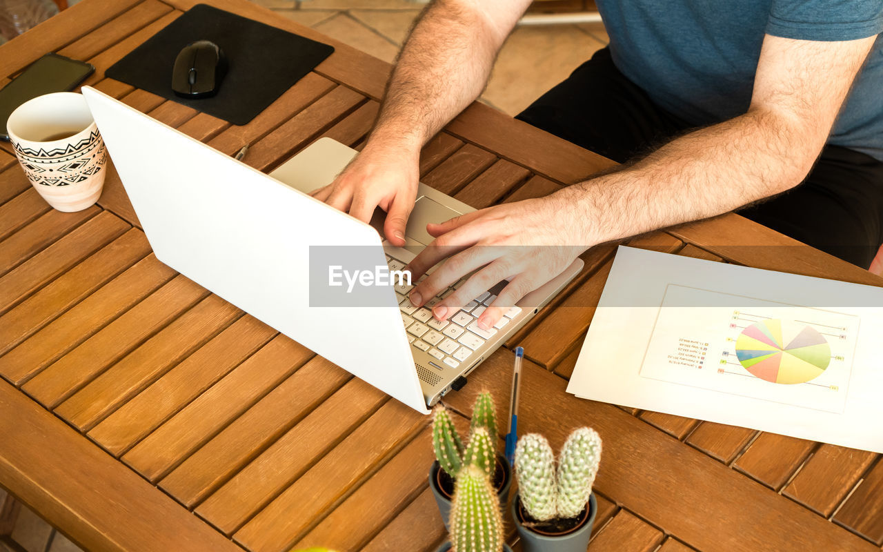 HIGH ANGLE VIEW OF MAN USING LAPTOP