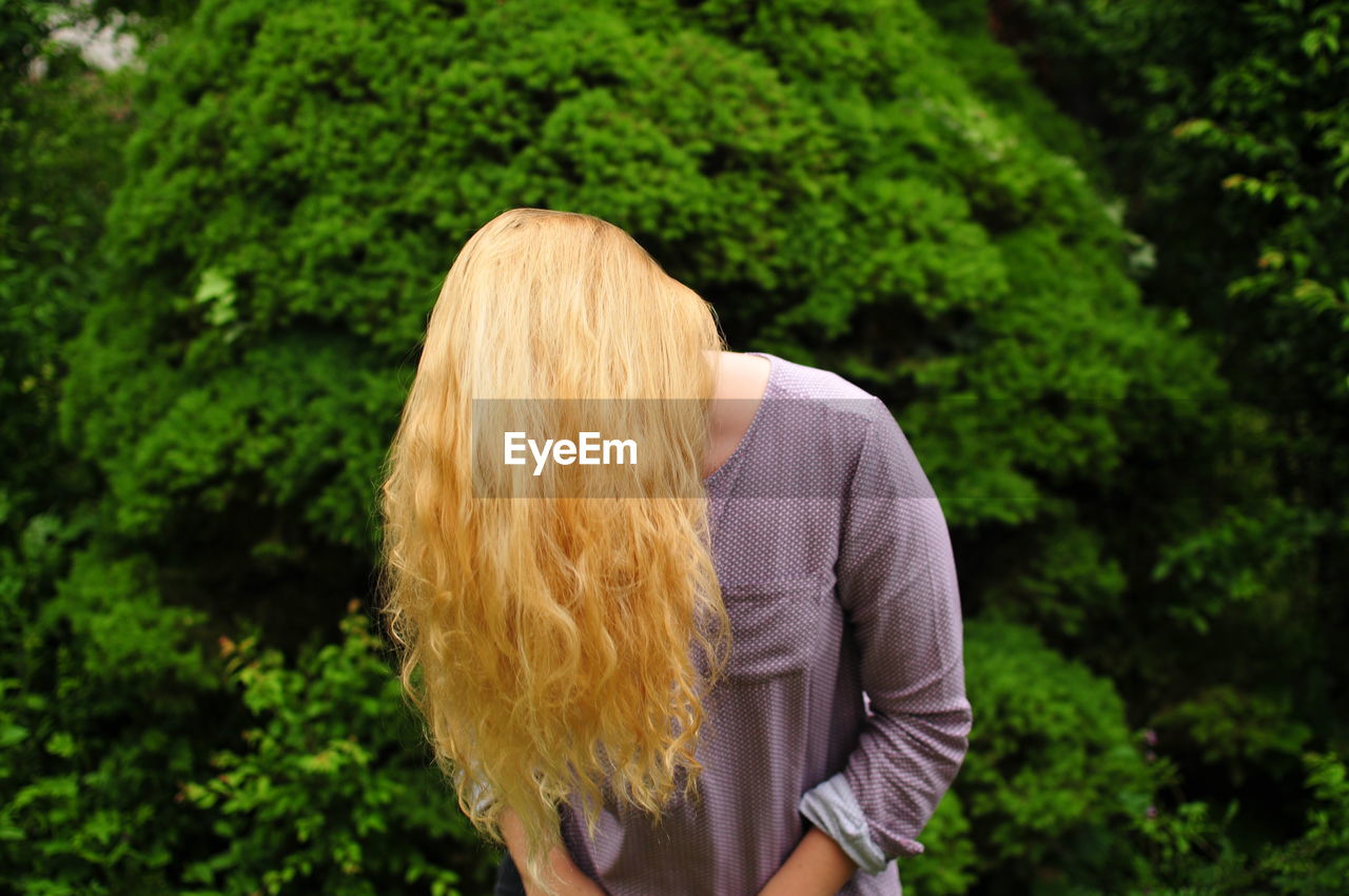 Woman covering face with long blond hair