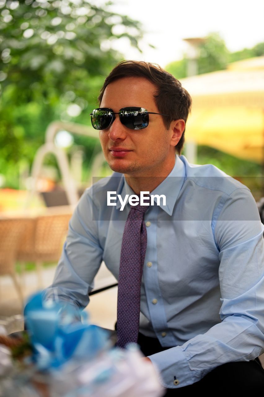 A handsome man formally dressed sitting in a cafe