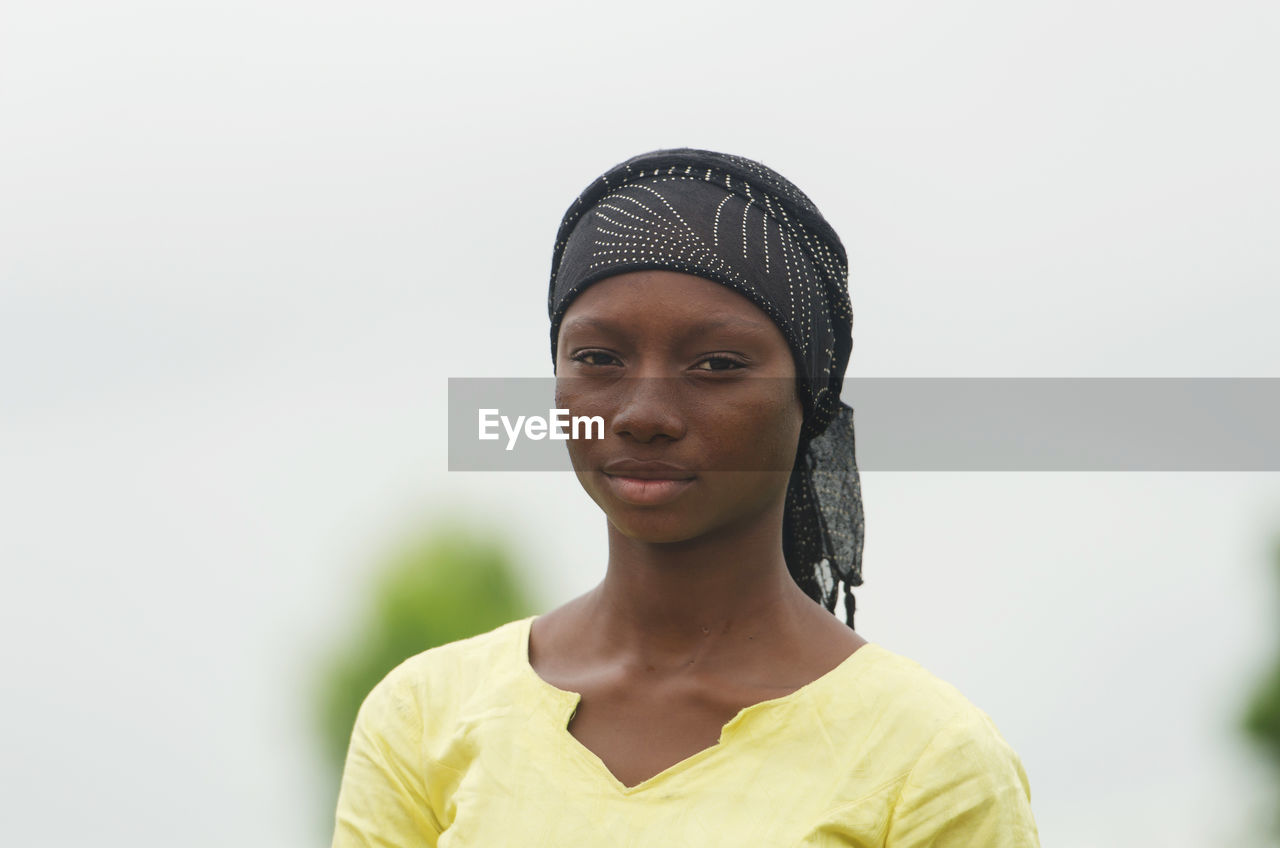 Portrait of young woman wearing headscarf standing against clear sky