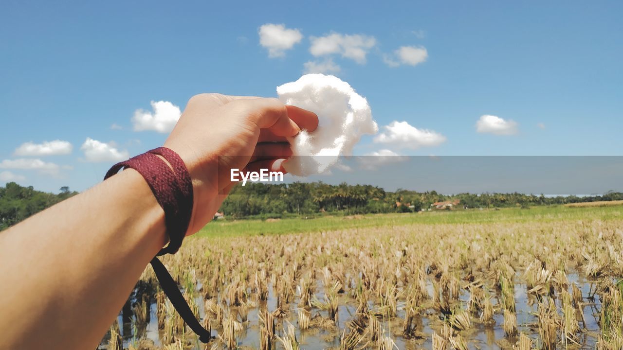 Midsection of person holding hands on field against sky