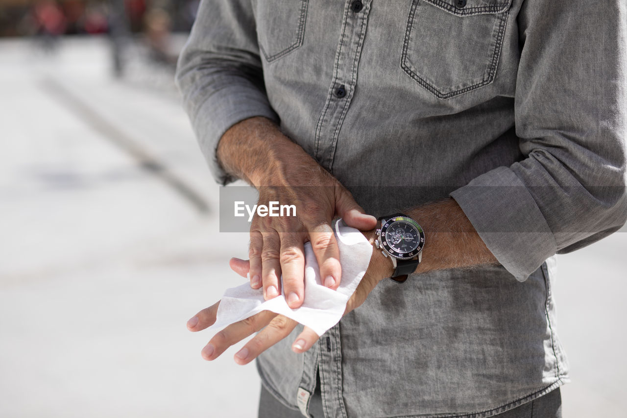 Old man cleaning hands with wet wipes, white