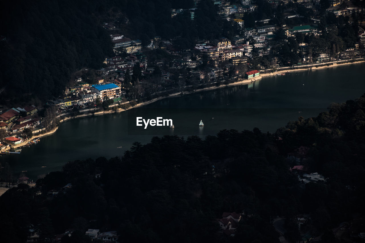 HIGH ANGLE VIEW OF ILLUMINATED CITY BY TREES AT NIGHT