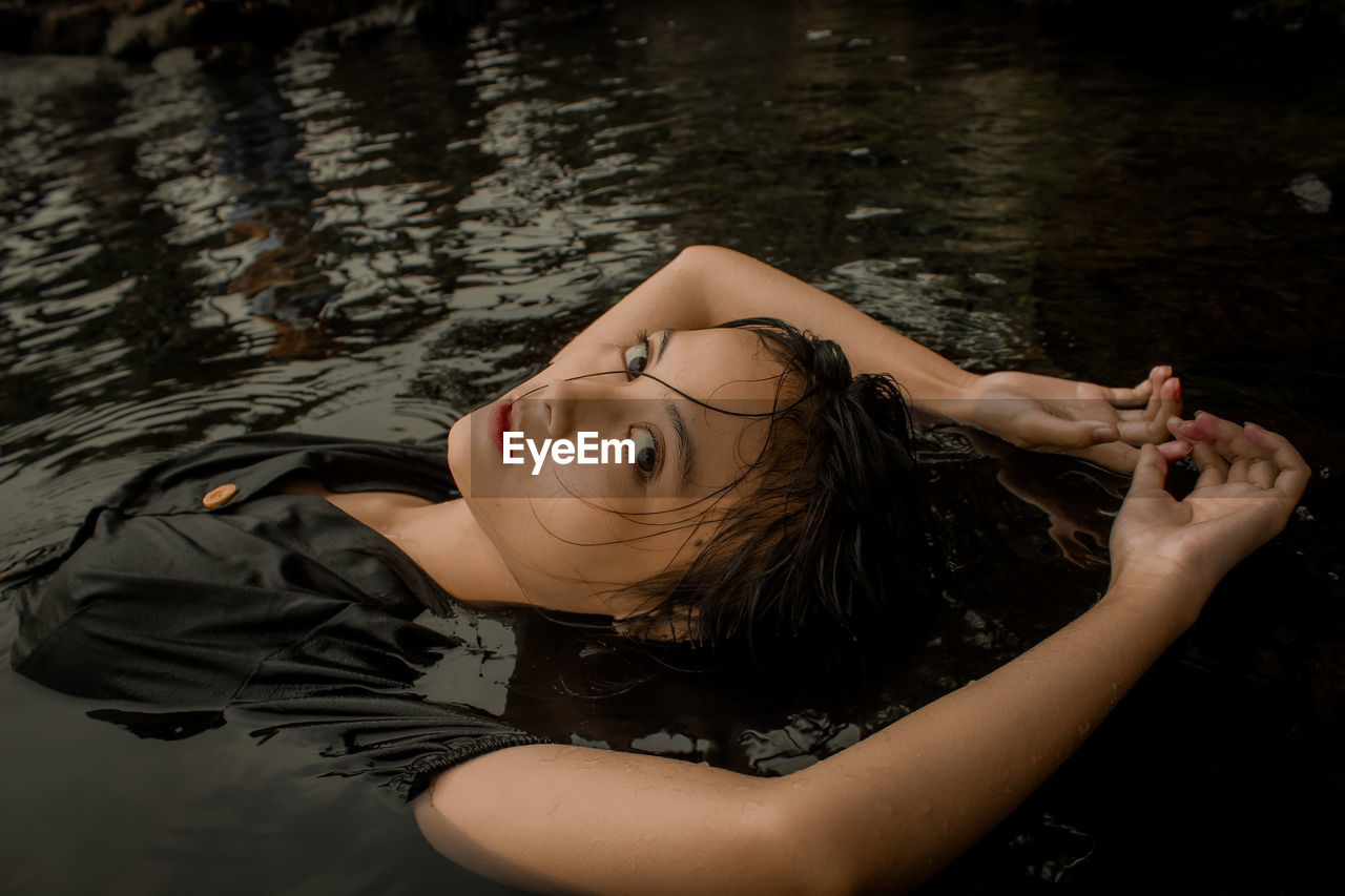 High angle portrait of woman lying down floating on water