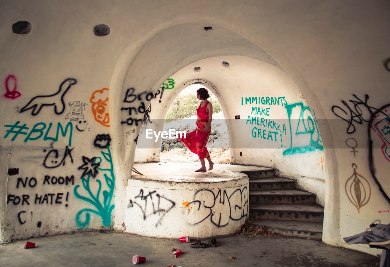 MAN STANDING BY GRAFFITI ON WALL